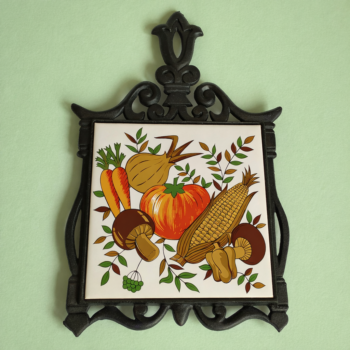 Vintage ijzeren (pannen) onderzetter van Woolco met op de tegel afbeelding van groenten