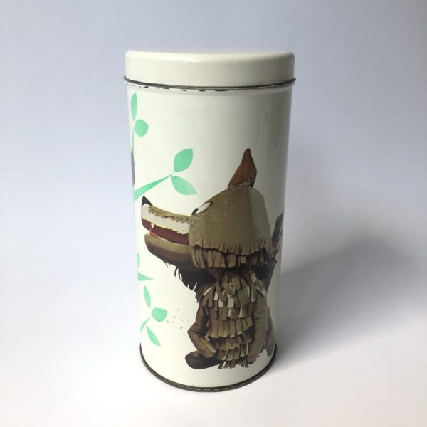 Beschuitbus Fabeltjeskrant uit 1969 - hoogte 22,5 cm - diameter 10,5 cm (2) De Fabeltjeskrant was een populair Nederlands kinderprogramma dat voor het eerst op televisie verscheen in 1968. Het werd bedacht door Leen Valkenier en gemaakt door de Nederlandse televisieproducenten op basis van het idee om een "krant" voor kinderen te creëren met verhalen over dieren in een fantasierijke wereld. De show draaide om de belevenissen van diverse dieren in het dierenbos, die de actualiteit en gebeurtenissen in hun eigen 'wereld' in de vorm van een krant bespraken. De hoofdfiguur was Meneer de Uil, die het nieuws presenteerde en vaak vergezeld werd door andere karakteristieke dieren zoals Juffrouw Ooievaar, Bor de Wolf, en andere kleurrijke figuren. Wat de Fabeltjeskrant bijzonder maakte, was de combinatie van educatieve elementen en humor, evenals de innovatieve manier waarop het gebruikmaakte van poppen en animatie. Het programma was niet alleen geliefd bij kinderen, maar ook bij volwassenen vanwege de scherpe en vaak satirische humor. De show heeft een grote invloed gehad op de Nederlandse kindertelevisie en blijft een nostalgisch icoon voor velen. Na de oorspronkelijke uitzendingen in de jaren '60 en '70, zijn er verschillende pogingen gedaan om het concept nieuw leven in te blazen, waaronder een aantal herhalingen en speciale afleveringen.