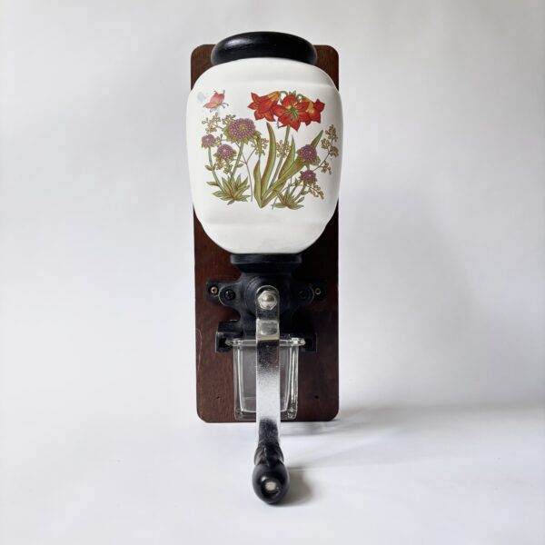 Wandkoffiemolen met een porseleinen trechter met bloemmotief (1) Vintage decoratieve wandkoffiemolen uit de jaren 70 met een porseleinen trechter met bloemmotief en een glazen opvangbakje