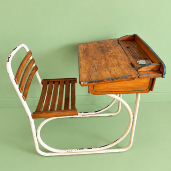 Vintage kinderlessenaar / schoolbank van het merk Torck uitgevoerd in hout met een metalen buizenframe en een opklapbaar schrijfblad